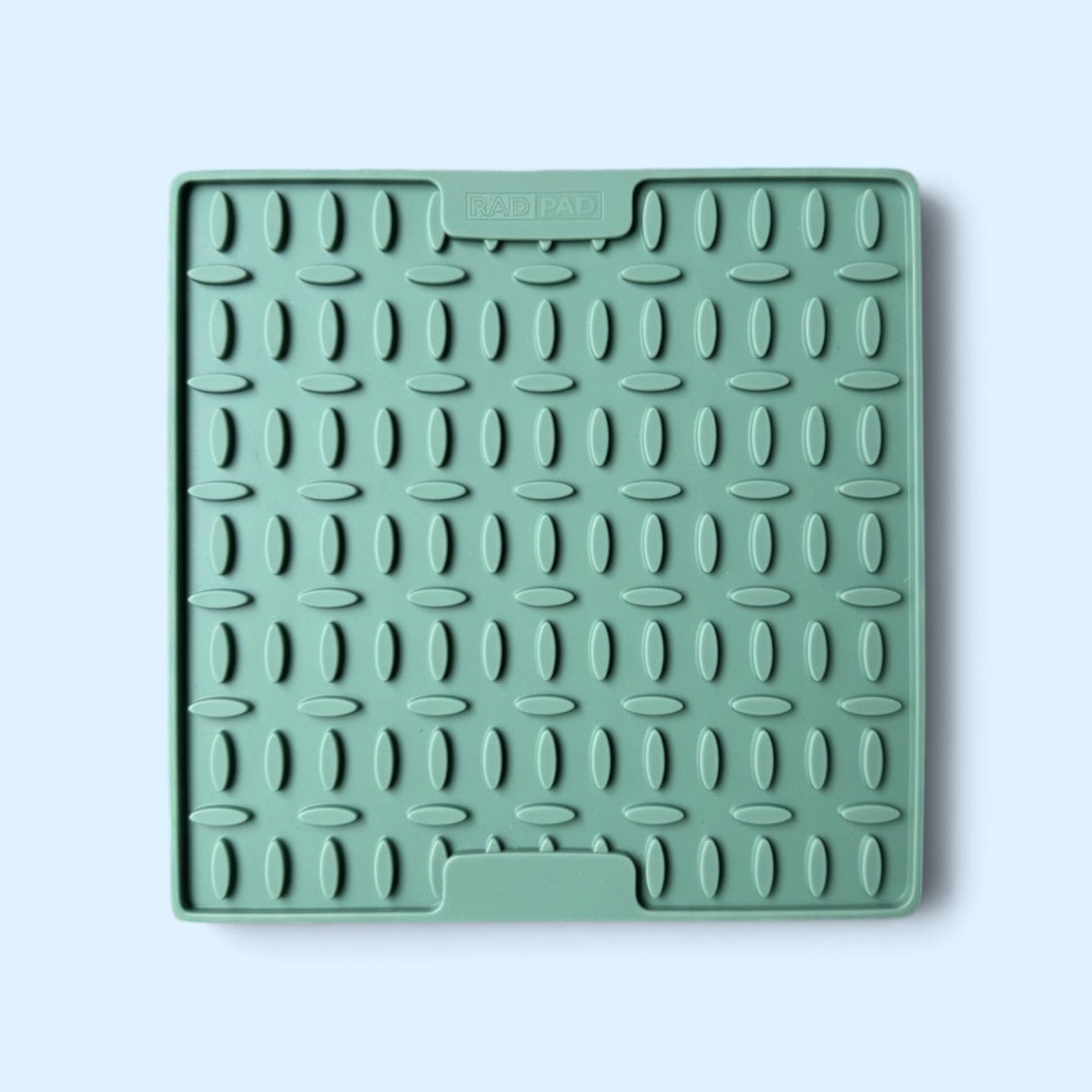 A square mint green silicone dish drying rack with a textured grid pattern, shown on a light blue background.
