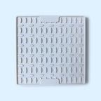 A square white silicone or rubber dish drying rack mat trivet with a textured grid pattern and two integrated handle slots, shown on a light blue background.